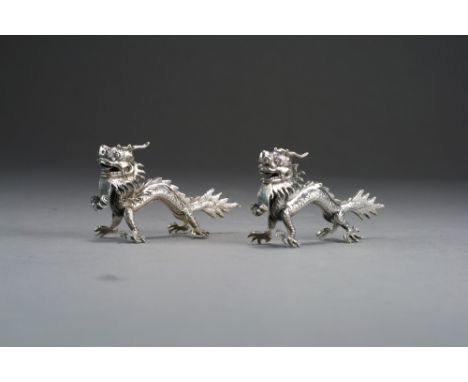 A pair of Chinese silver dragon menu or place holders, circa 1900, unsigned, modelled as fearsome four-clawed standing dragon