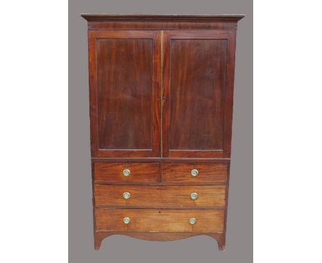 A George IV mahogany linen press, second quarter 19th century, the ogive cornice above two indented panel cupboard doors encl