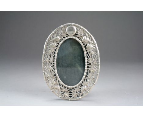 A Chinese silver photograph frame, circa 1900, of oval shape and with pierced decoration chased with birds nestling amid leaf