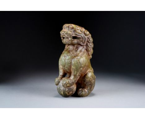 A large Chinese green and russet jade figure of a guardian lion, Qing Dynasty, with tightly curled mane and wearing a medalli