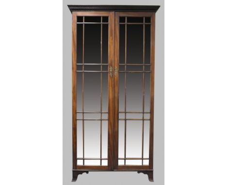 A mahogany free standing cabinet bookcase, 19th century, the dentil moulded ogive cornice above two full length glazed ribbed