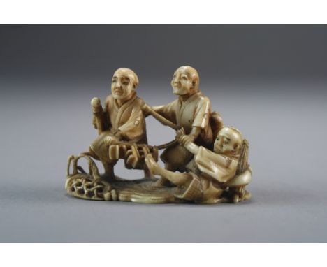 A Japanese ivory netsuke of fishermen, Meiji period, modelled as three men pulling at their broken net, signed to a red table