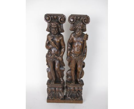 A pair of 17th Century carved oak Pilasters of bearded figures holding trident and mallet, scallop bases, 17in