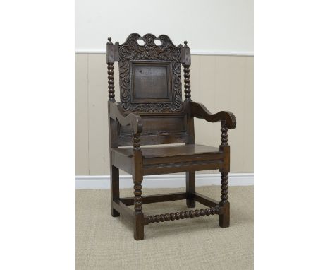 A Charles II oak Wainscot Armchair with leafage scroll carved cresting rail, plain square panel back flanked by bobbin turned