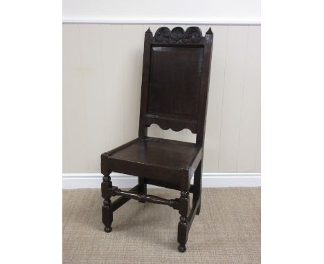 A 17th Century oak Side Chair with scroll and rosette carved top rail, plain panel back, solid seat on turned and square fron