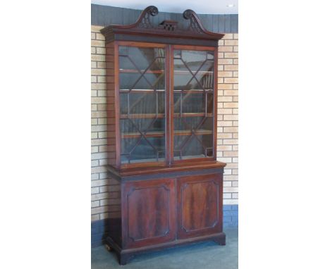 A 19th Century mahogany and astragal glazed two door Bookcase with pierced swan neck pediment above base fitted pair of panel