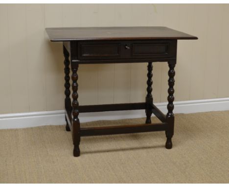 An antique oak Side Table fitted shallow frieze drawer with moulded panels on bobbin turned frame united by square stretchers