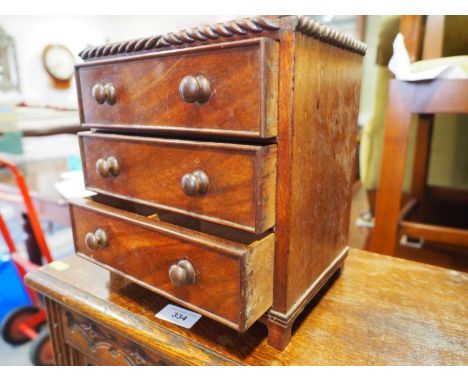 A mahogany miniature chest of three long drawers, on bracket feet, 11 1/2" wide