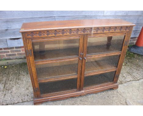 A carved oak bookcase enclosed two glazed doors, on bracket feet, 47" wide x 10 1/2" deep x 38" high, and a two-tier folding 