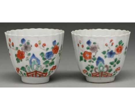 Two Chinese famille verte fluted cups, Kangxi period, painted with flowering plants growing from a hollow rock, the interior 
