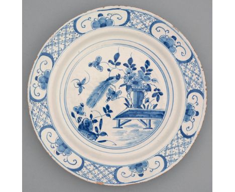 A Dutch Delftware dish, 18th c, painted&nbsp; after a Kangxi original, with a bird and flowers in panelled diaper border, 33c