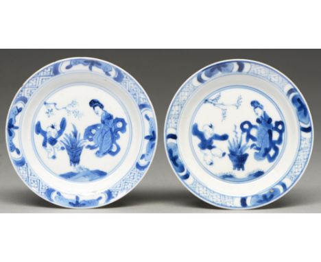 A pair of Chinese blue and white miniature plates, Kangxi period, painted with a woman and jumping boy in panelled diaper bor