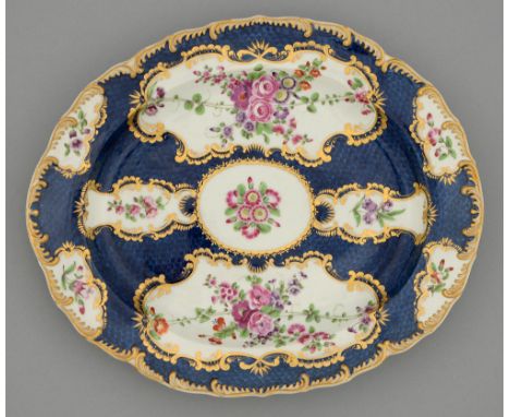 A Worcester scale blue ground dish, c1770, painted with flowers in gilt reserves and gilt feather moulded border, 30cm l, scr