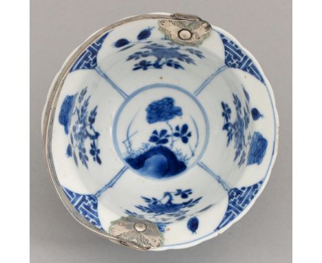 A Chinese blue and white bowl, Kangxi period, painted with auspicious objects alternating with flowering plants, adapted as a