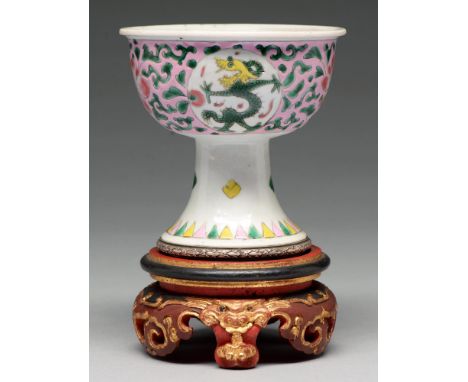 A Chinese famille rose stem cup, the bowl enamelled with dragon roundels and peonies on a pink ground, the flared foot with F