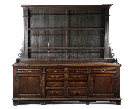 A LARGE EARLY GEORGE III OAK DRESSER C.1760-70 the architectural plate rack with fluted pilasters and pierced scroll corbels,