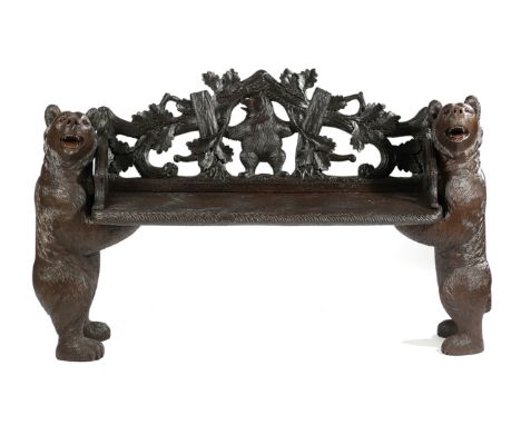 A BLACK FOREST CARVED WOOD BEAR BENCH FIRST HALF 20TH CENTURY the seat with an arched back decorated with oak leaves, branche