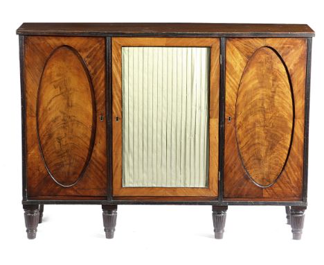 A GEORGE III MAHOGANY SIDE CABINET C.1800 with reeded decoration, with a pair of oval panelled doors, each enclosing a shelf,