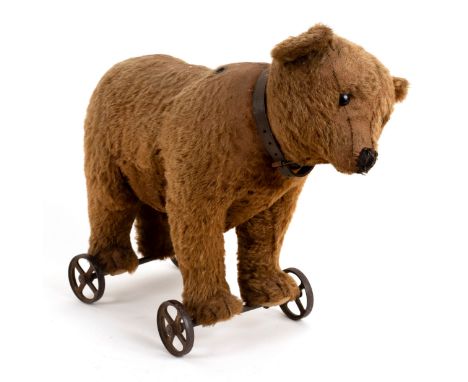 A Steiff bear on wheels, circa 1909, with movable head, collar and brown plush fur, on metal spoke wheels, 35cm high/see illu