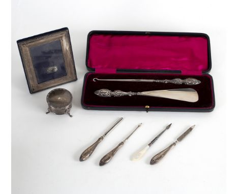 A silver handled shoe horn and button hook, Birmingham 1901, in a fitted case, a silver handled three-piece manicure set, a t