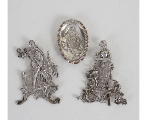 A pair of white metal figures, gallant with companion, on easel supports, 9cm high and an oval embossed portrait of Henry VII