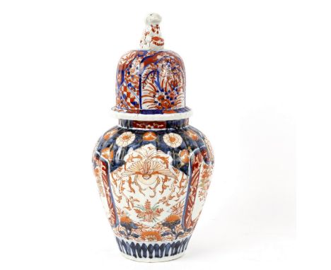 A Japanese Imari vase and cover of reeded form, painted reserves of garden landscapes, the cover with Dog of Fo finial, 41cm 