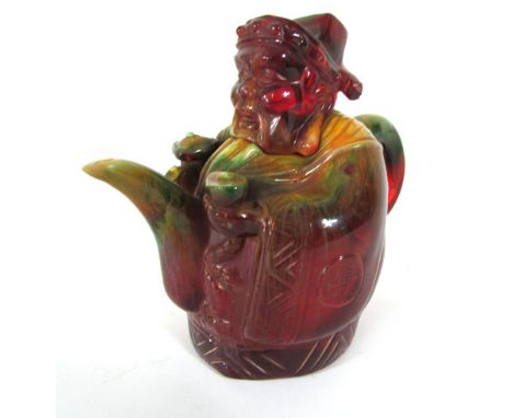 A Chinese cast resin teapot and modelled in the form of an immortal carrying a septre in mottled tones of red, yellow and gre