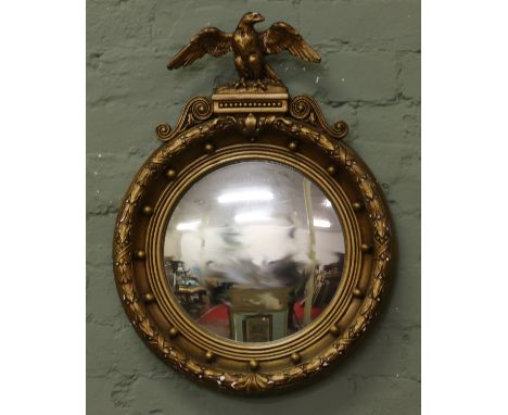 A Regency style gilt framed convex wall mirror surmounted with an eagle finial 