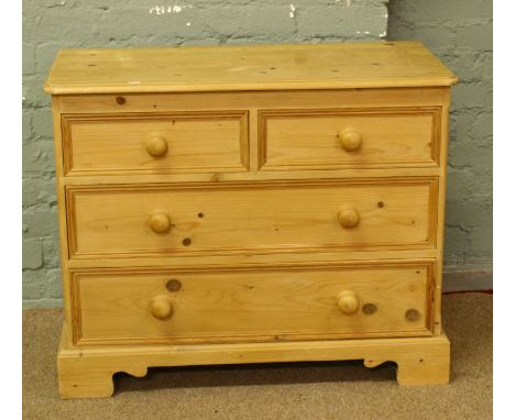 A pine chest of drawers with turned handles and bracket feet.