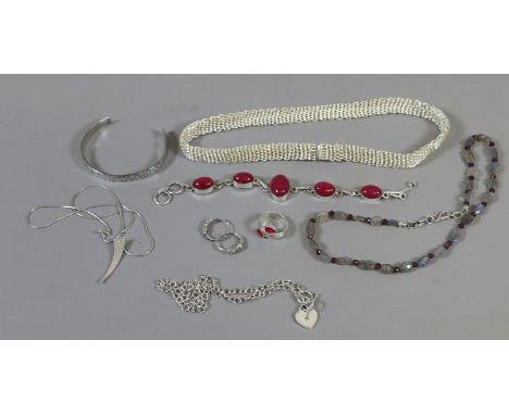 A collection of silver jewellery including heavy woven necklace, ruby crossover ring and a similar cabachon bracelet.