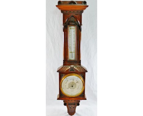 A late 19th century carved walnut wall mounted aneroid barometer with thermometer, the barometer with silvered dial and brass