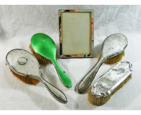 A plain silver photograph frame, Birmingham 1919, 14.8cm x 10.9cm, with wooden easel back, three silver backed hair brushes a