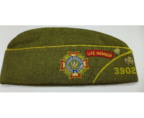A U.S. Veterans and Foreign Wars cap with cloth patch, two metal badges including one marked 10k