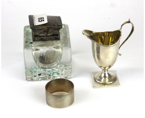 A hallmarked silver cream jug with a silver topped inkwell and a hallmarked silver napkin ring.