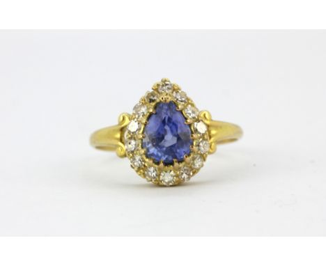 An 18ct yellow gold (stamped 18ct) ring set with a pear cut sapphire surrounded by single cut diamonds, (M).