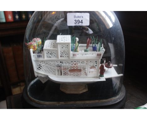 A CHINESE EXPORT BONE MODEL OF HOUSEBOAT with polychrome decoration, 9" long x 5.75" high, under a glass dome with a wooden b