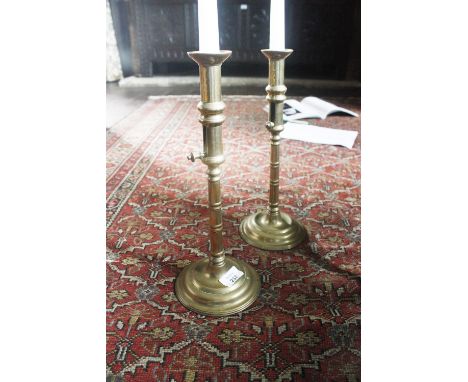 A RARE PAIR OF LARGE GEORGE II BRASS CANDLESTICKS with domed circular bases supporting ring-turned stems with push-up ejector