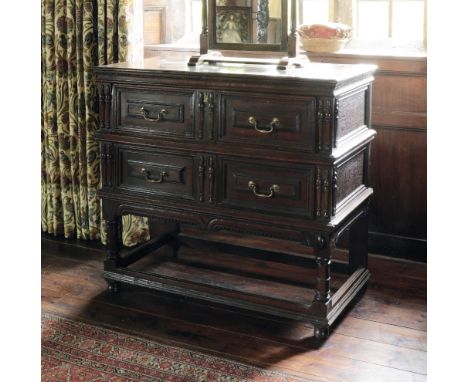 A CHARLES II OAK CHEST ON STAND, the rectangular top with a moulded and carved edge over two panelled drawers applied with sp