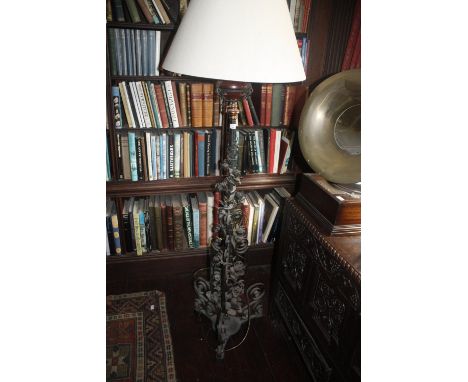A VICTORIAN WROUGHT IRON STANDARD LAMP on a triform base decorated with flowers and foliage, previously an oil lamp and still