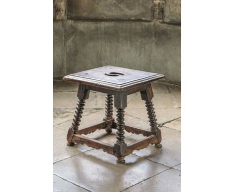 AN HISPANIC WALNUT STOOL, late 17th century, the square top with pierced carrying apertures and a moulded edge, on splayed bo