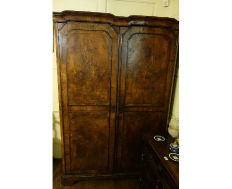 A GEORGE I STYLE WALNUT WARDROBE with a shallow double-dome moulded cornice over two doors, each composed of two raised panel