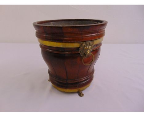 A tapering circular brass and wood planter with brass lion mask ring handles and brass feet circa 1840