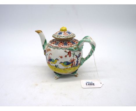 An unusual antique richly decorated teapot and cover with mask decoration, entwined handle and painted with various motifs, r