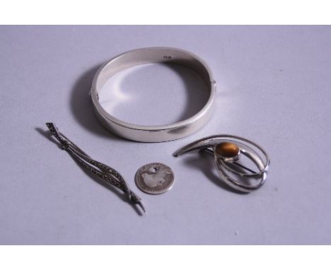 A SILVER BANGLE, approximate weight 17.5 grams, two brooches and a holed coin (4)