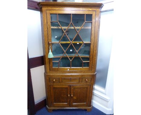 A 19TH CENTURY OAK ASTRAGAL GLAZED CORNER CUPBOARD, the base with single drawer and twin solid panelled doors and bracket fee