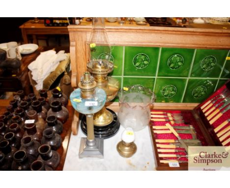 A brass oil lamp with glass shade together with one other and a small oil lamp