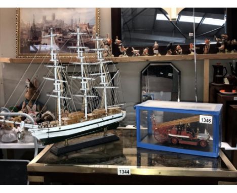 A plastic model kit assembled of a 1914 Dennie fire engine and a model of a sailing ship