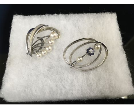 TWO WHITE METAL PEARL BROOCHES ONE SET WITH A SOLITAIRE DIAMOND SURROUNDED BY BLUE STONES