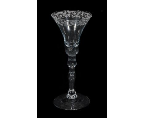 A Newcastle light baluster wine glass, mid 18th century, the bell bowl engraved with stylized foliate band, the solid lower s