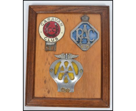A group of three vintage 20th century motoring related car badges all mounted to a board set within an oak frame. The badges 